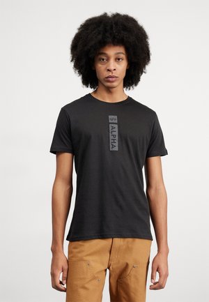 T-shirt noir à manches courtes en coton, avec un graphique central portant le mot "ALPHA" et un col rond.