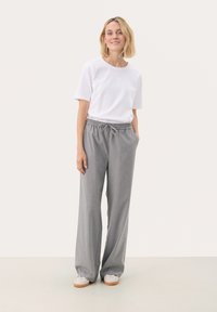 Lightweight white cotton t-shirt with short sleeves paired with loose, gray, textured, long trousers featuring an elastic waistband and drawstring.