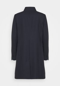 Marinblå ullkappa med en strukturerad krage, långa ärmar och en texturerad yta. Har en enda mittsöm och kontrasterande foder.