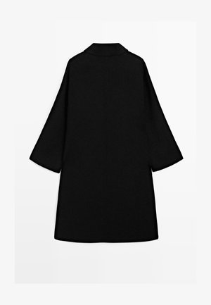 Cappotto nero fino al ginocchio con maniche larghe e collo semplice, mostrato disteso con la parte posteriore rivolta in avanti su uno sfondo bianco.