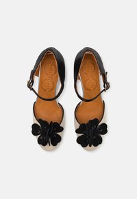 Pantofi cu brâu de gleznă din material textil negru, cu vârf crem, având un accent floral mare negru. Tălpic din piele. Formă curbată, talpă plată.