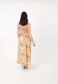 Blomster maxi kjole med justerbare spaghetti stropper; har orange, gule og blå blomster på en lys baggrund. Smocked rygdetalje.