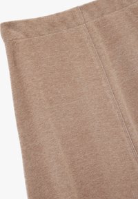 Beige strikkede leggings med en blød tekstur og elastisk talje. Har en glat overflade og synlige sømme langs siderne.