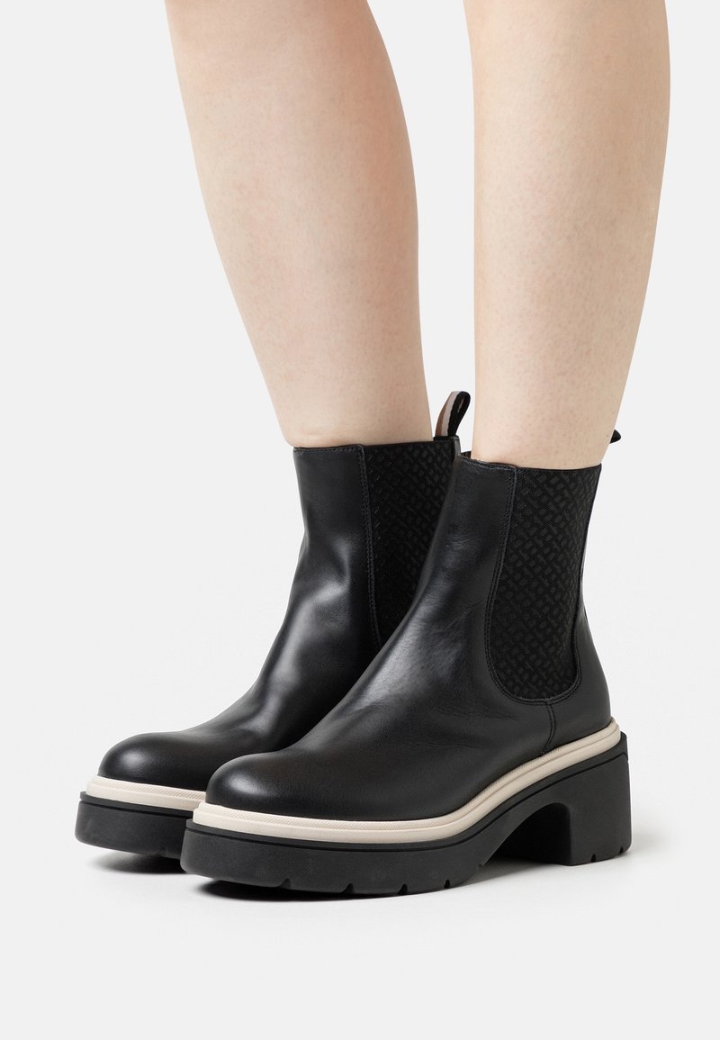 Botas de tobillo de cuero negro con un panel lateral elástico texturizado, suela de plataforma gruesa y una pestaña trasera para facilitar el calzado.