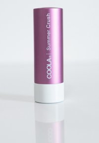 Rosa zylindrischer Behälter mit weißem Boden, beschriftet mit "COOLA Summer Crush." Glatte metallische Oberfläche, reflektierender Effekt.