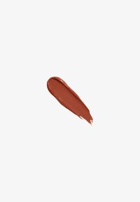 Échantillon de crème cosmétique de couleur rouille avec une texture lisse, appliqué en ligne courbe, sur fond blanc.