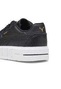 Black leather sneaker with a textured surface, white rubber sole, and gold PUMA logo on the heel. Features a lace-up design for adjustment.