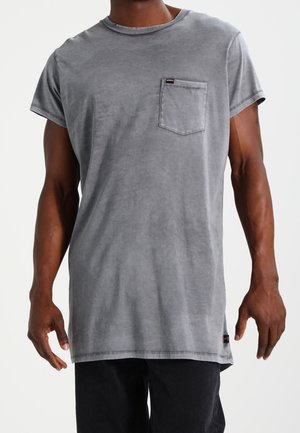 Graues Baumwoll-T-Shirt mit einer Brusttasche, kurzen Ärmeln und Rundhalsausschnitt. Strukturierte Oberfläche und unversäuberter Saum.