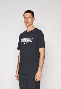 T-shirt in cotone nero con maniche corte e scollatura rotonda. Presenta testo bianco che recita "VINCERE INIZIA CON UN ALLENAMENTO" e logo Nike.