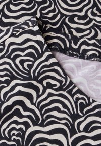 Bavlněná tkanina s černobílým vířivým vzorem růží. Ploché švy podél výstřihu a okrajů. Měkká textura s lehkým elastickým efektem.