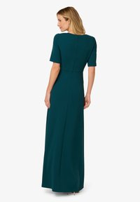 Tyrkysové maxi šaty s krátkými rukávy, přiléhavým korzetem a rovnou sukní. Obsahují zip na zadní straně a hladkou, texturovanou látku.