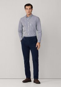 Gestreept overhemd in blauw en wit, gecombineerd met donkerblauwe chino's en bruine instappers; gladde stof en slim fit.
