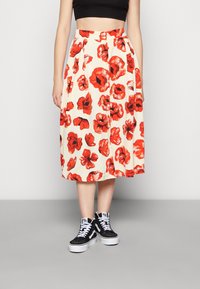 Kukkakuvioinen midi-hame kermanvärisenä, jossa punainen unikon kuvio; siinä on istuva vyötärönauha ja laskokset. Yhdistetty mustiin korkeavartisiin tennareihin.