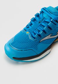 Scarpa da ginnastica blu con tomaia in mesh testurizzato, punta rinforzata e suola in gomma nera. Presenta lacci intrecciati e marchio SLAM.