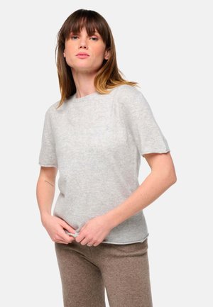 Chemise légère grise à manches courtes en tissu doux. Dotée d'un col rond et d'une coupe décontractée, elle est associée à un pantalon marron texturé.