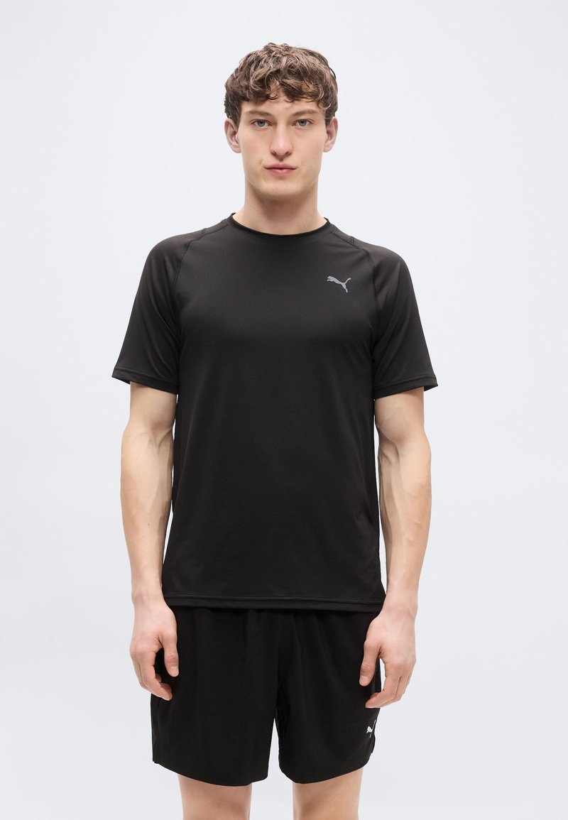 Μαύρο αθλητικό πουκάμισο με κοντά μανίκια και στρογγυλή λαιμόκοψη, με μικρό γκρι λογότυπο στο στήθος· σετ με μαύρα σορτς.