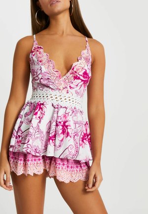 Blomstret peplumtop med dyb V-hals, blondekanter og en hvid hæklede taljebånd, kombineret med lyserøde mønstrede shorts med bølgede kanter.