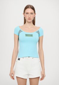 Light blue fitted t-shirt with short sleeves, scoop neckline, and gray mesh accents. Features a colorful graphic logo in the center.