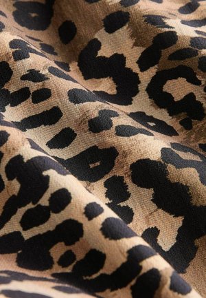 Leopardų rašto audinys su tan spalvos fonu ir ryškiais juodais taškais, pasižymintis lygiu tekstūru ir minkštu, audiniu dekoruotu paviršiumi.