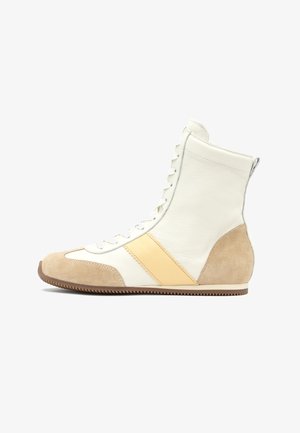 Fehér magas szárú sportcipő bézs színű velúr orr- és sarokpántokkal, bézs bőrcsíkkal, fehér fűzőkkel és bordázott barna talppal.