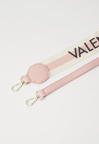 Pinkki ja kerma-valkoinen raitahihna, joka on valmistettu kankaasta ja nahasta, varustettuna kultaisilla kiinnikkeillä ja pyöreällä kiinnityspisteellä. Teksti "VALENTINO" sijoitettu näkyvästi.