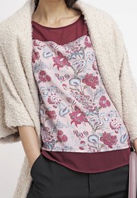 Haut floral avec des sections roses et bordeaux ; texture douce ; motifs complexes comprenant des fleurs et des feuilles ; aspect en couches avec un bas foncé.