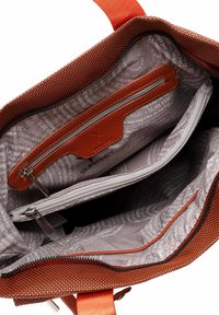 Pomarańczowa torba o fakturze z zamkiem błyskawicznym, z gładkim brązowym wnętrzem i wieloma przegródkami, w tym kieszenią na zamek.
