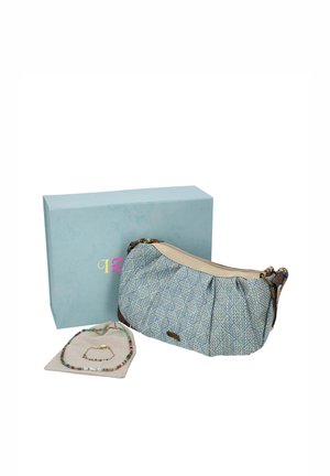 Bolso bandolera azul estampado, collar y pulsera de cuentas de colores sobre una base de exposición, con una caja de marca azul claro detrás.