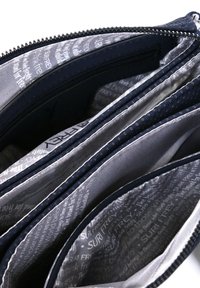 Portafoglio blu navy con zip e molteplici scomparti; l'interno presenta una fodera liscia con un motivo di testo ripetuto; esterno testurizzato per una migliore presa.