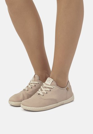 Sneakers in tela beige con punta rotonda, suola in gomma strutturata, lacci bianchi e un piccolo logo accento vicino al tallone.