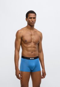 Blauwe boxershorts met een zwarte tailleband waarop "BOSS" staat. Soepele textuur en strak design, met een moderne stijl en een nauwsluitende pasvorm.