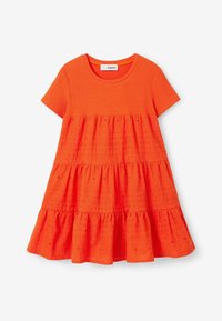 Žebrované krátké šaty s krátkými rukávy v jasně oranžové barvě. Mají vrstvený střih s texturovanou látkou a vlnitým lemem zdobeným vzory otvorů.