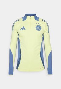 Maglietta sportiva a maniche lunghe di colore giallo fluorescente con pannelli laterali blu, colletto con mezza zip e un logo con stelle sul petto.