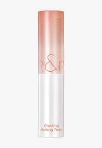 Genomskinlig plasttub med en gradient av rosa och orange upptill och vit bas. Har orange text som säger "Glistening Melting Balm." Elegant, cylindrisk design.