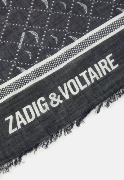 Melnā šalle ar baltām paisley rakstiem, ar teksturētu apmalu un pušķotām malām. Zīmola nosaukums "ZADIG&VOLTAIRE" ir izcili redzams.