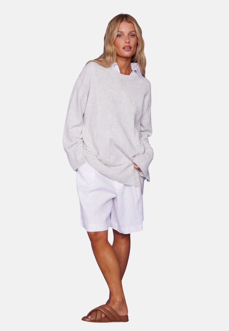 Lys grå oversized genser med senkede skuldre, hvite linshorts og brune slidesandaler. Glatt tekstur, avslappet passform, uformell design.