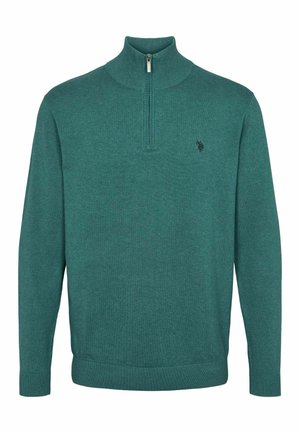 Tummansininen neulepusero, jossa on korkea kaulus ja puoliveto. Ominaisuuksiin kuuluvat ribbireunukset hihoissa ja helmassa sekä pieni logo rinnassa.