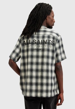 Black and white plaid short-sleeve shirt with "ALLSAINTS" and Japanese text on the back, made from a textured fabric.