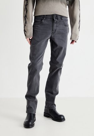 Grå denimjeans med rett benklipp, fem lommer og belteløkker, sammen med svarte ankelstøvler og en teksturert genser med lange ermer.