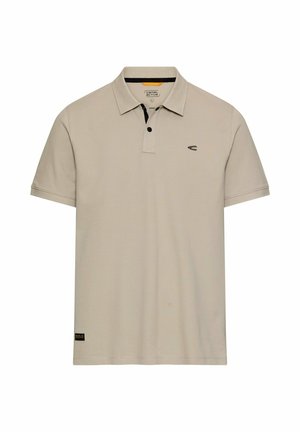 Polo beige à manches courtes avec patte de boutonnage noire, petit logo sur la poitrine et écusson de marque près de l'ourlet.