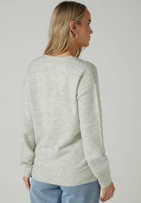 Maglione lavorato a maglia grigio chiaro con maniche lunghe, collo rotondo e orlo a coste. Tessuto morbido con leggere variazioni di trama.