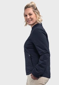 Marineblau isolierte Jacke mit Stehkragen, Reißverschlusstaschen und gestepptem Design. Verfügt über ein dezentes Logo am Ärmel und einen glatten Finish.