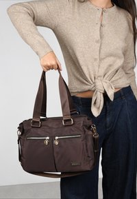 Bolso de mano de nailon marrón con dos bolsillos delanteros con cremallera, detalles en hardware dorado, asas dobles y una correa de hombro desmontable.