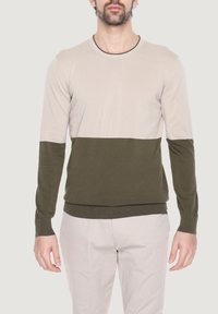 Maglione lavorato a maglia con collo rotondo, caratterizzato da un corpo beige chiaro e una parte inferiore verde oliva scuro. Maniche lunghe con polsini a coste.