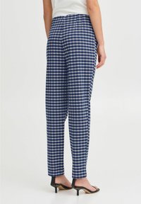 Pantalons à carreaux navy en tissu léger, coupe droite et taille minimaliste. Présente un motif de grille blanche contrastant.