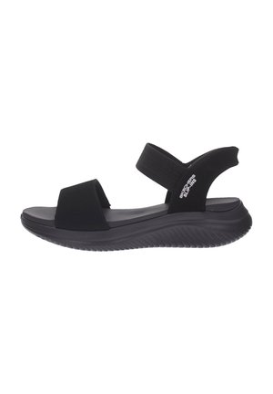 Sandalo nero slip-on con suola imbottita, cinturino elastico alla caviglia e punta aperta, con il marchio "Skechers Slip-Ins" sulla fascetta laterale.