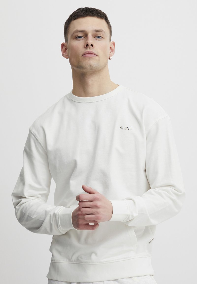 Witte lange mouwen sweatshirt van zacht materiaal. Heeft ribgebreide manchetten en een zoom. Klein logo op de borst. Eenvoudig, schoon ontwerp.