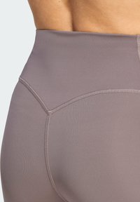 Κολάν με ψηλή μέση και εφαρμοστή γραμμή σε απαλό λαβαντί χρώμα, με λεία υφή, επίπεδες ραφές και διακριτική λάμψη.