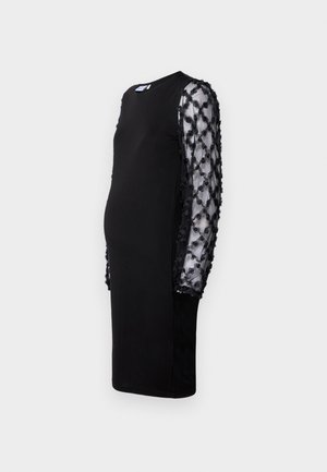 Svart kjole med solid kropp og gjennomskinnelige svarte ermer med hevede blomsterapplikasjoner. Rund hals og midtlengde design.