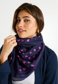 Bufanda azul marino con patrones de corazones rosas y un borde delgado rosa en contraste, hecha de una tela suave y dispuesta en un drapeado elegante alrededor del cuello.